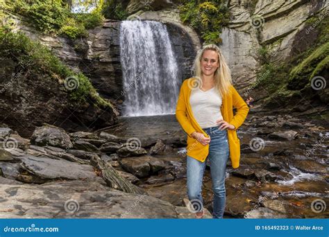 A Lovely Blonde Model Enjoys An Autumn Day Outdoors At A Park Near A Waterfall Stock Image