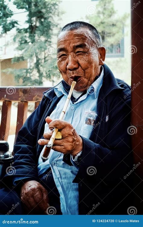 Chinese Man Smoking A Long Pipe With A Cigar Calmly During The