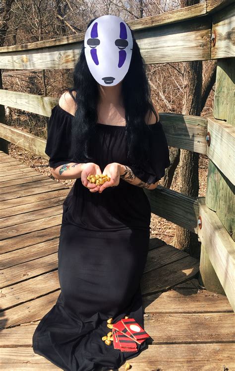 A Woman With Long Black Hair Wearing A White Mask Sitting On A Wooden Bridge Holding Food