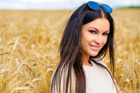 Young Brunette Woman On A Background Of Golden Wheat Field Summer