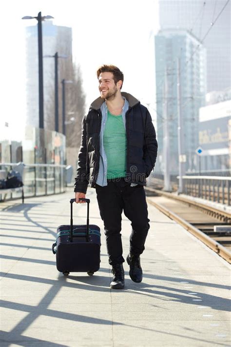 Молодой человек усмехаясь с чемоданом на платформе вокзала Стоковое Изображение изображение