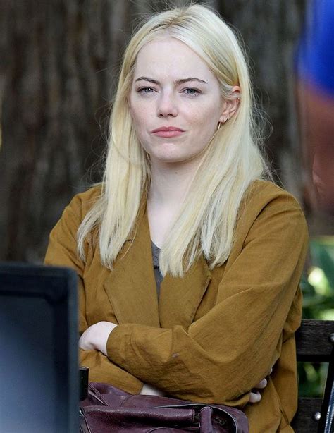 A Blonde Woman Sitting On A Bench In Front Of A Tree With Her Arms Crossed