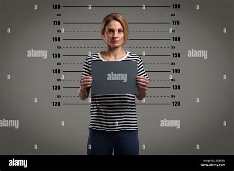 Criminal mugshot. Arrested woman with blank card against height chart