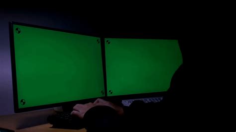 Young man from behind sitting at a table with a computer with a green screen, and also a green chroma screen in the background. Hacker Using Computer Green Screen With Tracking Marker ...