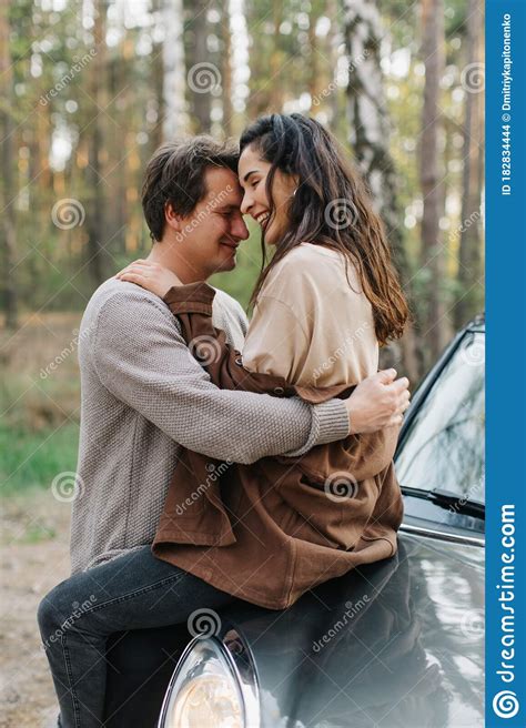 Beautiful Young Couple In Love Kisses Sitting On A Car Stock Photo