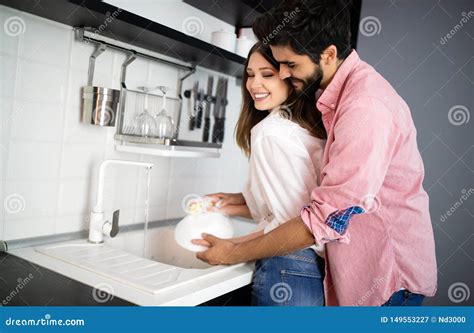 Young Happy Couple Is Washing Dishes While Doing Cleaning At Home