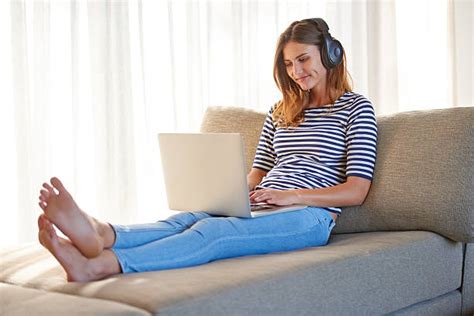 Royalty Free Woman With Bare Feet On Sofa Listening To Mp3 Player