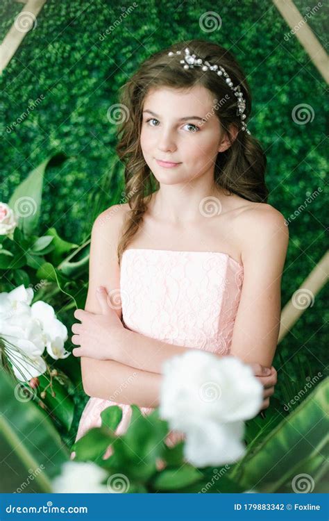 Attractive Young Girl In A Romantic Pink Dress Among Tropical Greenery And White Orchids Roses