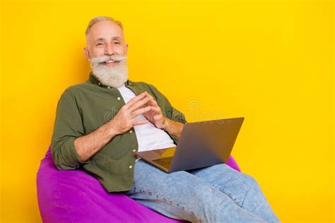Photo Of Mature Old Programmer Sit Beanbag Hold Pc Beaming Smile Wear