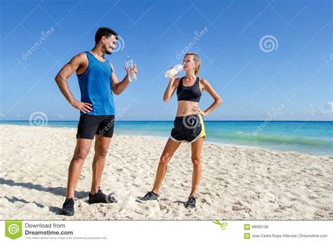Runners Couple Drinking Water After Training At The Beach