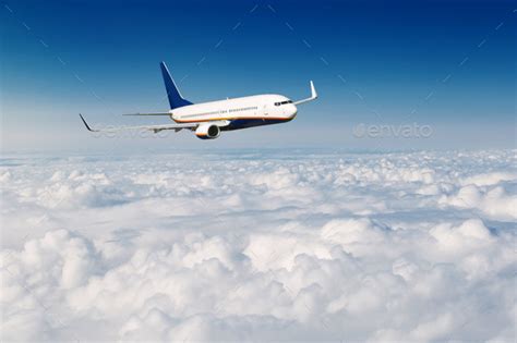 Commercial Airplane Flying Above Clouds On Blue Sky Background Stock