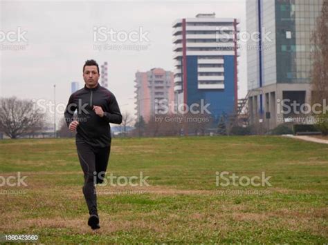Adult Man Running In The Parc In Winter With City Background Stock
