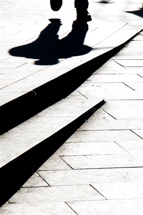 Blurry Silhouette Shadow Of A Man Walking On A City Sidewalk With Steps