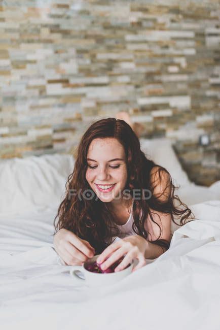Girl Lying In Bed And Eating Fruits Looking Down Bed Lines Stock