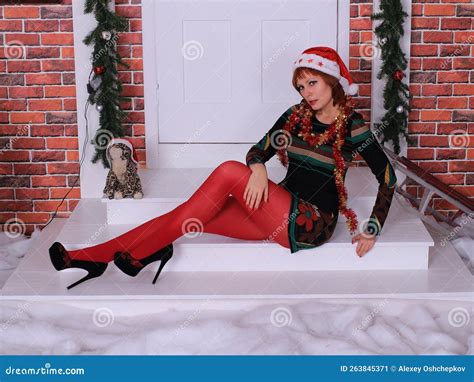 Beautiful Long Legged Redhead Girl In Red Stockings And Heels Posing In Christmas Decoration