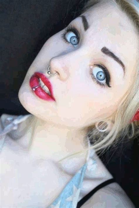 A Woman With Blue Eyes And Piercings On Her Nose Is Posing For The Camera
