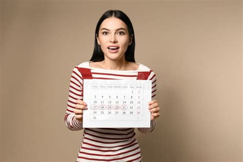 Young Woman Holding Calendar With Marked Menstrual Cycle Days On