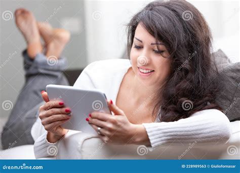 Attractive Woman Relaxing On A Sofa Reading On A Tablet Stock Image Image Of Feelings Black