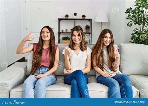 Group Of Three Hispanic Girls Sitting On The Sofa At Home Doing Happy