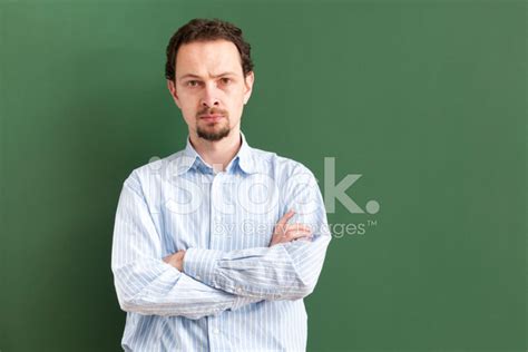Serious Teacher Standing With Arms Crossed At Blackboard Stock Photos