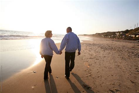 Elderly Couple Holding Hands And Walking On The Beach Stocksy United