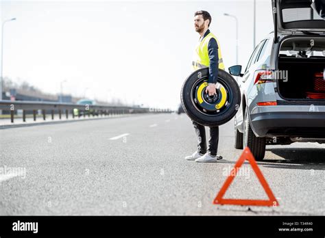 Man Changing Wheel Standing With Spare Wheel Near The Broken Car On The Roadside Stock Photo Alamy
