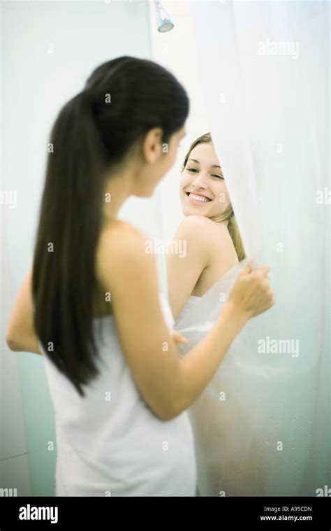 Young Woman Taking Shower While Friend Holds Open Shower Curtain Stock