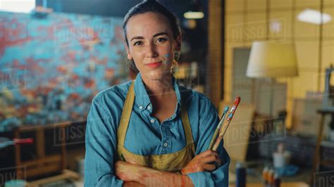 Young Female Artist Dirty With Paint Wearing Apron Crosses Arms While