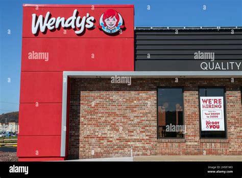 A "we're hiring" sign is seen on the window of a Wendy's fast food