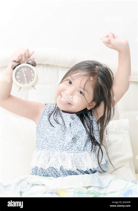 Cute Girl Wakes Up In The Morning With Alarm Clock In The Bedroom Stock