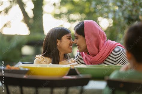 Affectionate Mother In Hijab Rubbing Noses At Dinner Table Stock Photo