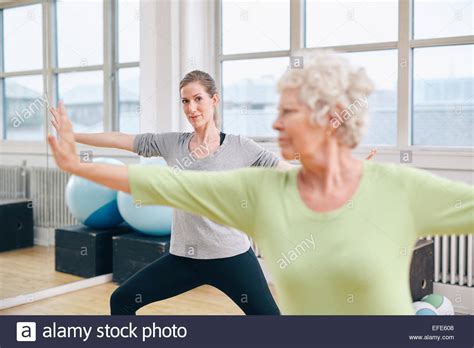 Two Women Doing Stretching And Aerobics Workout At Gym Female Trainer