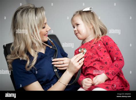 Female Doctor Examining Girl Sitting Against Gray Background Stock