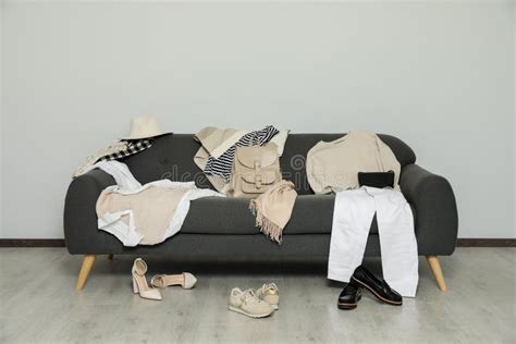Messy Pile Of Clothes On Sofa And Shoes In Living Room Stock Image