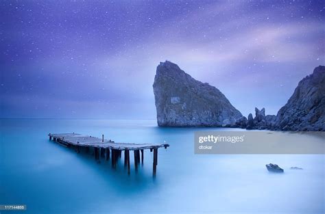 Sea At Night Under Milky Way Stars With Pier High Res Stock Photo