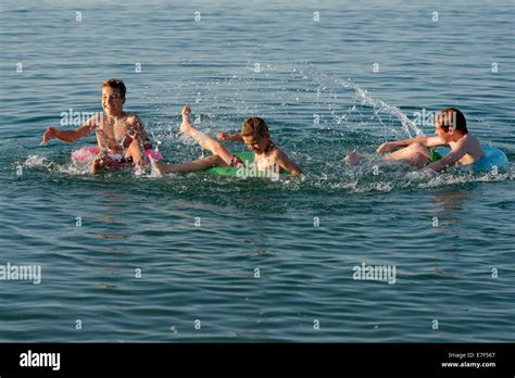 Water Fight Children Playing On Floating Tyres In The Sea