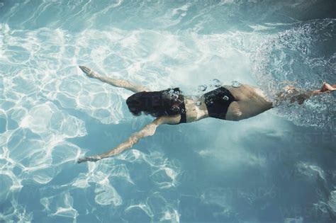Woman In Bikini Swimming Underwater In Sunny Swimming Pool Lizenzfreies Stockfoto