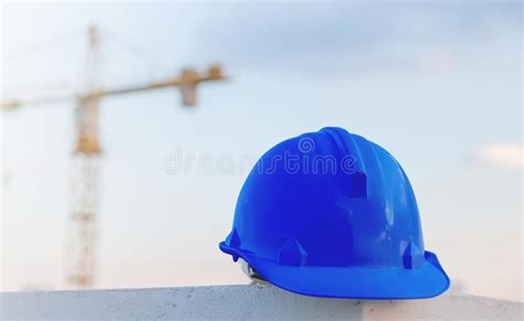 The Blue Safety Helmet At Construction Site With Crane Background Stock