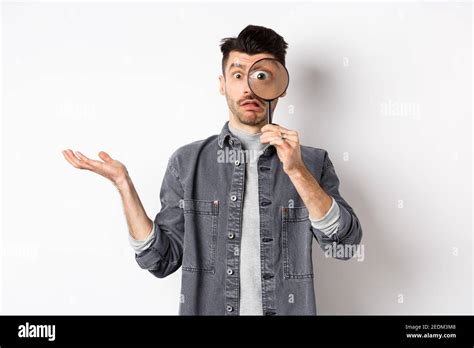 Confused Man Look Through Magnifying Glass And Shrugging Clueless