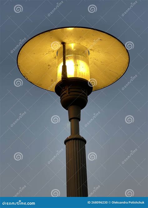 Vintage Street Lamp Glowing Yellow Against Evening Sky Stock Photo