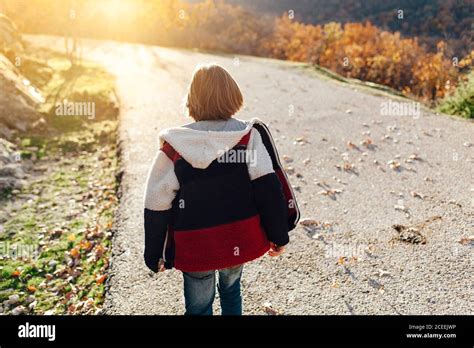 Back View Of Boy Walking Alone By A Path In The Countryside Stock Photo