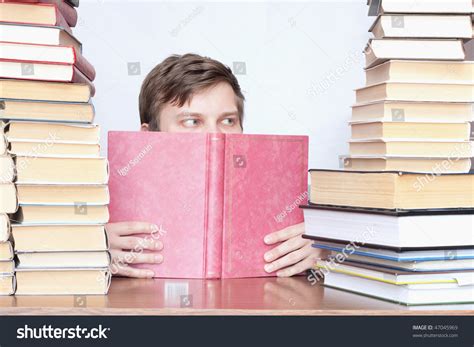 Young Student Reading Book And See Sideways Between Books Stock Photo