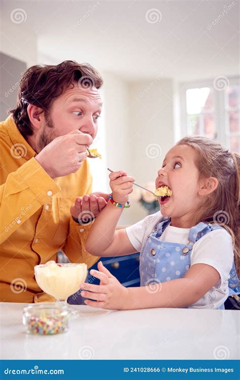 Padre E Hija En La Cocina Comiendo Postre De Helado Con Cuchara Foto De
