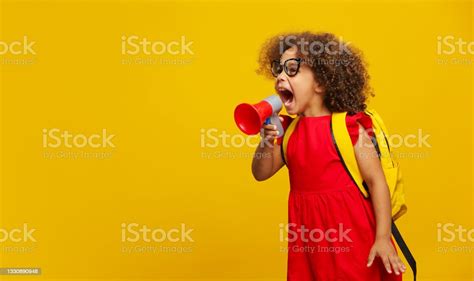 little cute black girl in red dress holding in hand and speaking in electronic gray megaphone