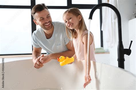 Father With His Cute Little Daughter Filling Tub In Bathroom Stock