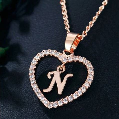 A Heart Shaped Initial Necklace With The Letter N In Its Center Surrounded By Diamonds