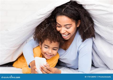 Feliz Madre Negra E Hija Usando El Smartphone En La Cama Foto de archivo Imagen de teléfono
