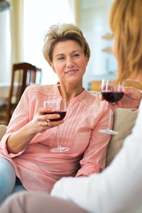 Mature Women Drinking Wine While Sitting In Sofa At Home Stock Image