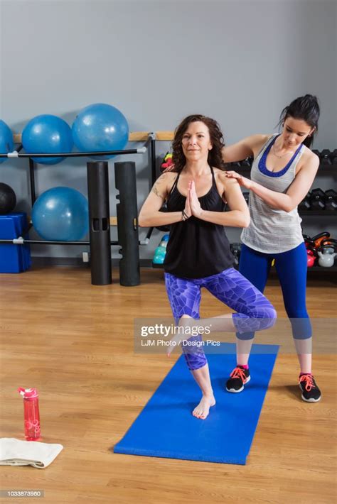 An Attractive Middleaged Woman Doing Yoga Exercises At The Gym With Her Personal Trainer