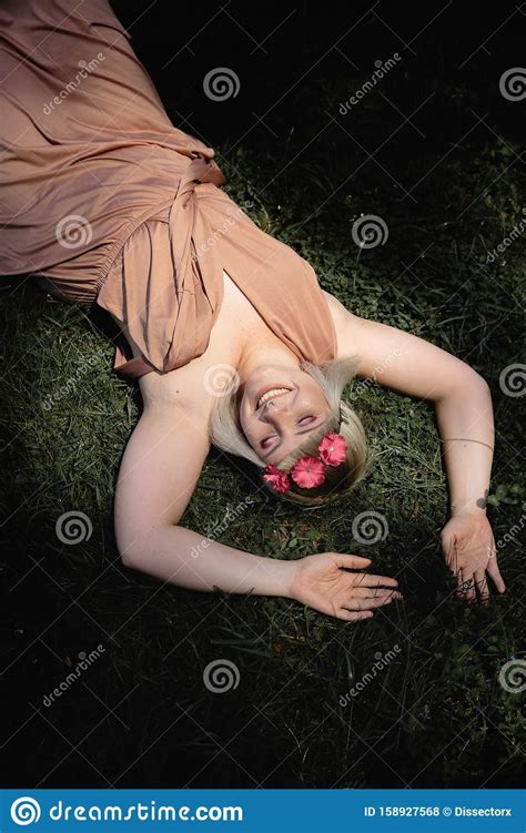 Hippie Woman Laying On The Grass In The Park Wearing Loose Beige Dress